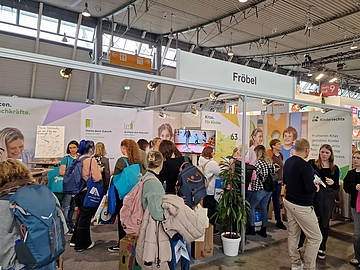 Messestand von Fröbel auf der didacta 2025. Viele interessierte Menschen schauen sich am Messestand um. Weitere Stände in der Halles sind zu sehen. 
